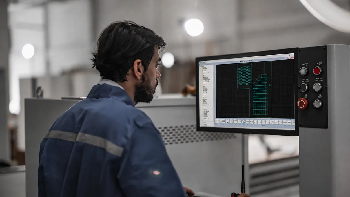 Operario observando un plano de corte anidado en la pantalla del panel de control de una máquina CNC.